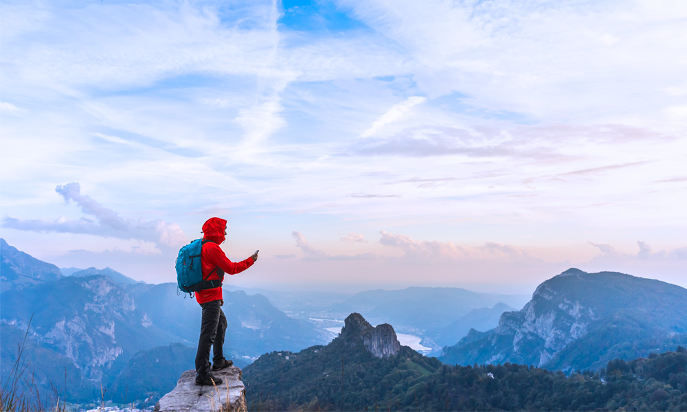 image of hiker on mountain looking at smartphone